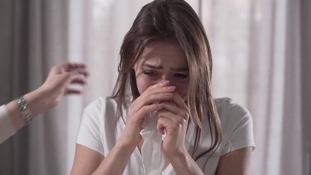 Close-up face of depressed Caucasian woman crying. Senior female hand caressing her hair. Mother calming down her adult upset daughter.