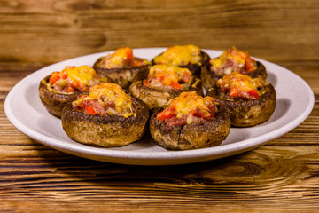 Baked champignons stuffed with minced meat and cheese in plate on a wooden table