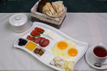tasty breakfast, honey, egg, sausage, olives, tomato and cucumber on the table