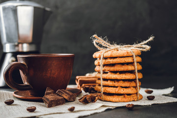 Homemade cookies and brown cup with coffee on dark background
