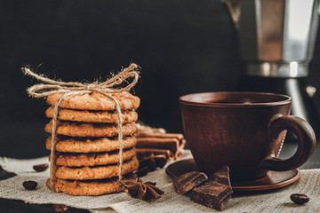 Homemade cookies and brown cup with coffee on dark background