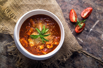 Appetizing homemade bowl of tomato soup served in a plate on a wooden table Copyspace Top view