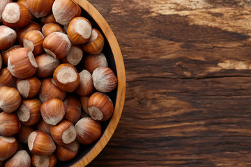Hazelnuts in wooden bowl on textured background