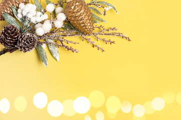Beautiful christmas decoration. Christmas tree branch and pine cones, on a yellow glitter background.