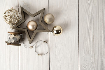 Wooden star with Christmas Golden balls and reel with ribbon of stars on white natural wooden background.