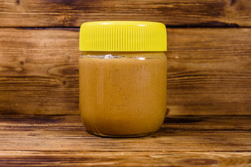Glass jar with peanut butter on a wooden table