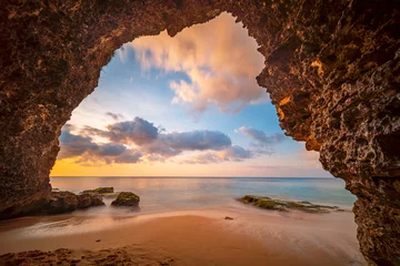 Foto auf Acrylglas Blick von der Höhle auf einen Sandstrand am Meer bei Sonnenuntergang © pozdeevvs