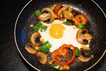 Freshly fried eggs with vegetables in a pan