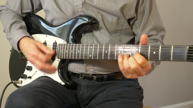 Playing a song up and down the neck of a guitar - wider view 4K
