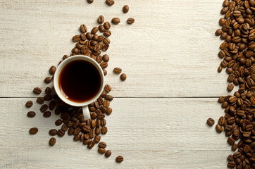 AromaticCoffee mug with roasted coffee beans on wooden table. View from top