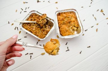 Indian food, fruit pies, subhadra and mithai, in foil plates on a white background, sprinkled with seeds, spices, piece of pie on fork in hand