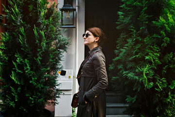 Outdoor portrait of a Caucasian woman with brown coat and sun glasses at sunset time.  