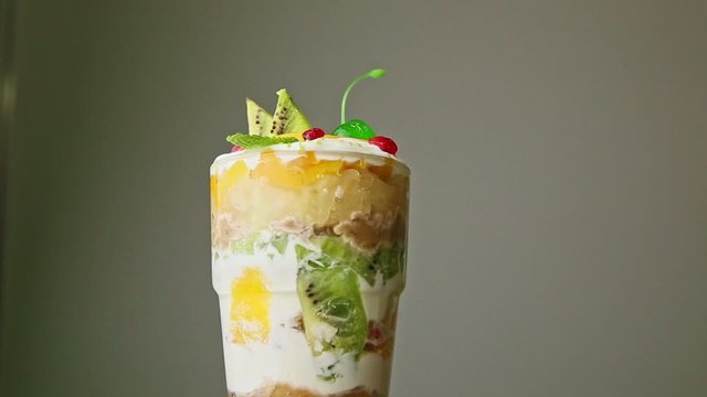 delicious layered fruit cream dessert in tall glass spinning around