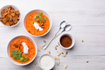Pumpkin dish with croutons, sour cream, pumpkin seeds, cilantro and spices on a white wooden background
