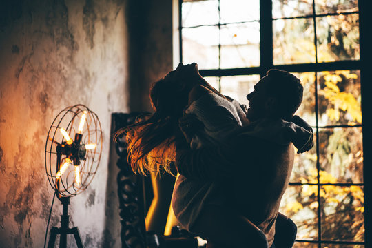 Young man holding woman in his hands. Couple in love at the home.