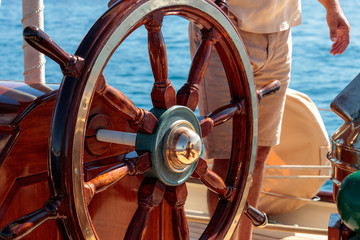 Classic Elegance: Close Up of Rustic Wooden and Gold Wheel on Sailing Yacht at Sea © SPIX PRODUCTION