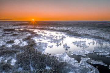 Aerial view on National park covered in first snow in Latvia. Warm sunlight lights up the frozen lake and islands.