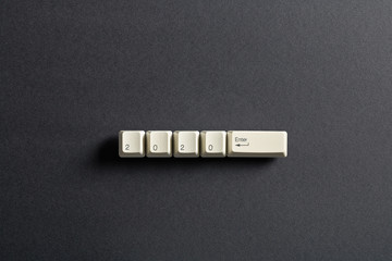 Computer keyboard keys with 2020 enter written using the white buttons on a dark background. Holiday technology concept. New year 2020 card.