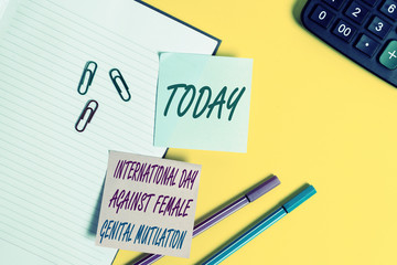 Text sign showing International Day Against. Business photo showcasing International Day Against Female Genital Mutilation Empty blue paper with copy space paper clips and pencils on the yellow table