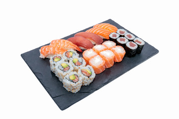 High angle shot of different sushi rolls on a black tray isolated on a white background