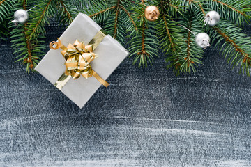 Christmas winter background, Christmas card. Fir branches, holiday decorations and gift or present box on a dark background, top view with space for text.