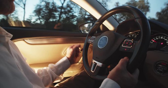 Shot for Animation. Male adult confident driver hand tapping cyberspace wheel dashboard, driving futuristic elegant car towards in summer twilight. Cyber technology. Auto control. Navigating online.