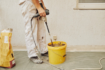 Construction worker using machine for plastering.