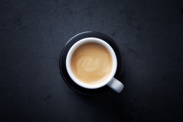 Cup of coffee on dark stone background. Top view. Copy space