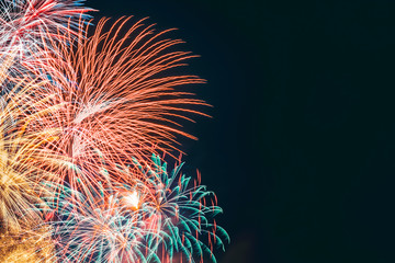 Beautiful festive explosions of multicolored fireworks in the dark sky during a celebration with...