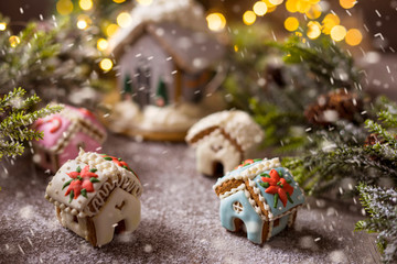 Gingerbread house on the background of a Christmas tree and a lie garland. Handling the effect of snowfall.