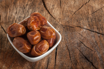 palm dates close-up on an old wooden background in a white plate top view