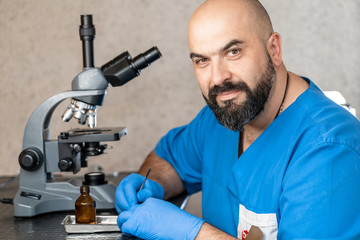 Male laboratory assistant examining biomaterial samples in a microscope.