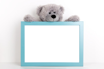 Interior poster mock up for nurcery, children's room with vertical wooden frame and teddy bear on white wall background