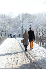 man and woman walk along the bridge together among the cold white landscape of the city of Munich in the snow, a park in winter, the concept of love, a happy marriage