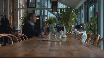 Boy play in virtual reality glasses, man is on his phone - Powered by Adobe