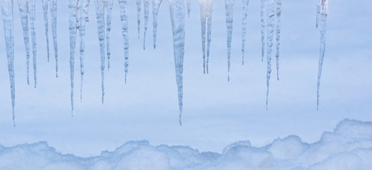 icicles hanging down over the snowy winter background covers