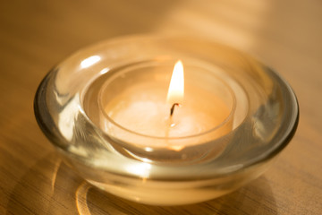 Obraz na płótnie Canvas low candle burns in a round glass candlestick, closeup.