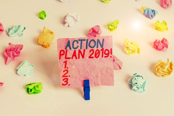 Conceptual hand writing showing Action Plan 2019. Concept meaning proposed strategy or course of actions for current year Colored crumpled paper empty reminder white floor clothespin