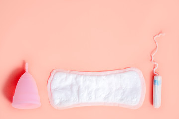 Menstrual cup, sanitary pad and swab on a pink background. Concept of menstruation, feminine hygiene products. Flat lay. copy spase