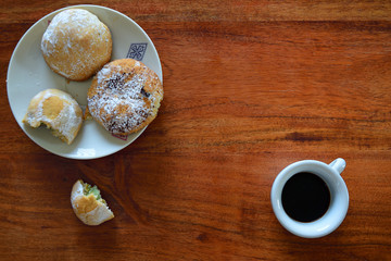 Obraz na płótnie Canvas A wooden table from above with a small plate of pastries and a cup of espresso for a break with room for text