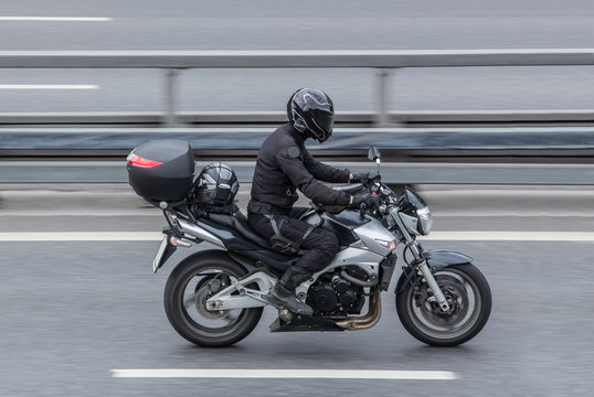 Motorcyclist in a helmet rides a motorcycle on the road.