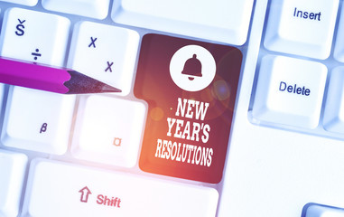 Conceptual hand writing showing New Year S Resolutions. Concept meaning Wishlist List of things to accomplish or improve White pc keyboard with note paper above the white background
