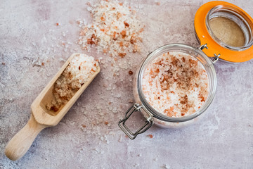 High angle close up of wooden spoon and glass jar with coarse salt.