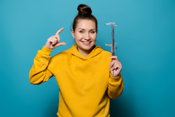 the girl depicts the magnitude with her fingers and shows the caliper in the other hand