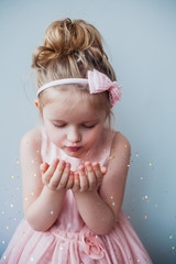 Portrait of cute 5 years old girl blowing gold glitter. Fairy Christmas concept.
