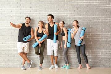 Obraz premium Group of people with yoga mats near brick wall