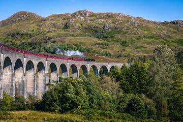 Obraz premium Widok na słynny wiadukt Glenfinnan z filmów o Harrym Potterze z czerwonym pociągiem Jacobi w Szkocji