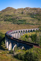 View on famous Glenfinnan viaduct from Harry Potter movies with red Jacobi train, Scotland