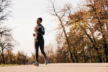  Zwarte atletische vrouw joggen in herfstdag in het park. © Drazen