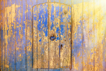 Ancient wooden door covered with blue cracked paint. Wooden wall of Arab house and door with knocker handle.